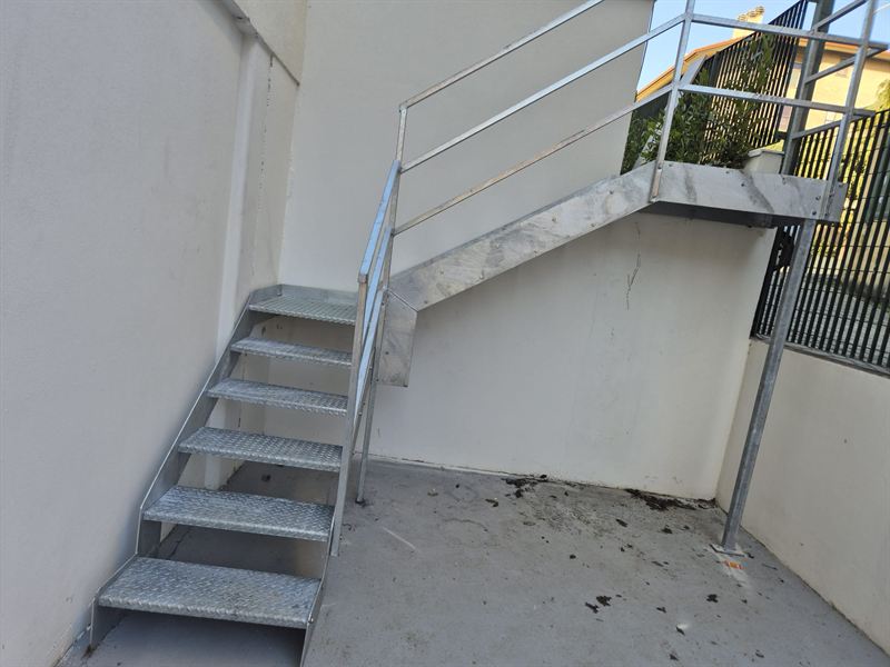 Scala esterna in acciaio zincato con gradini in lamiera mandorlata, pianerottolo e ringhiera